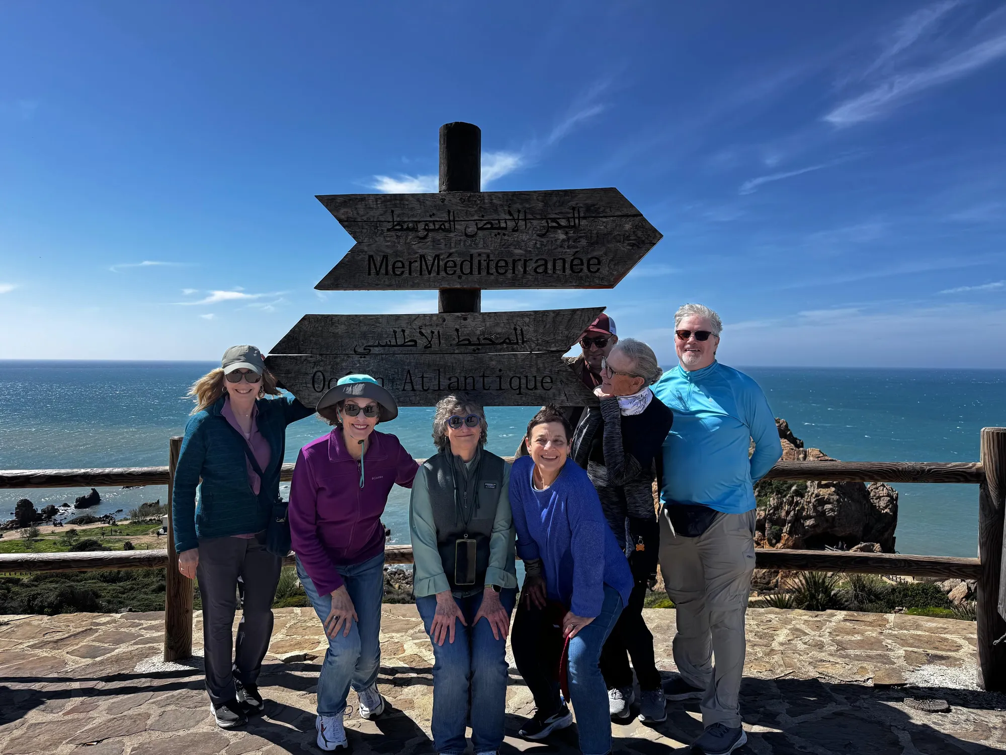 Travelers at a windswept signpost on the Atlantic coast